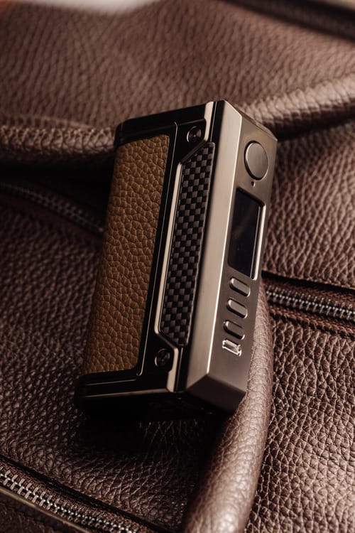 Luxury materials, gun metals device with brown leather inlays on a brown leather background